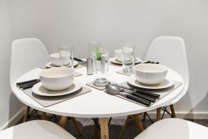 a white table with white bowls and plates on it at Stylish - Modern - Serviced Accommodation - In The Heart of Northumberland in Ashington