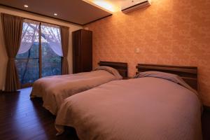 2 łóżka w pokoju hotelowym z oknem w obiekcie Sen-no-Mori w mieście Aso
