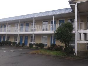 um edifício de apartamentos com portas azuis e um parque de estacionamento em El Rancho Motel em Little Rock