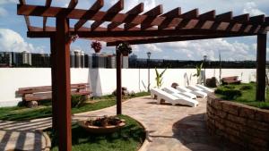 a group of white benches sitting under a wooden pergola at Apartamento Golden Dolphin Supreme Caldas Novas in Caldas Novas