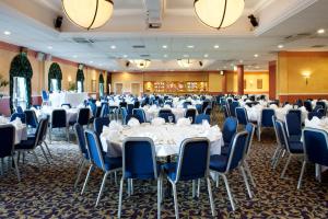 Holiday Inn Barnsley, an IHG Hotel في بارنسلي: قاعة احتفالات بالطاولات البيضاء والكراسي الزرقاء