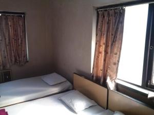 a small room with two beds and a window at Capital Guest House in Kolkata