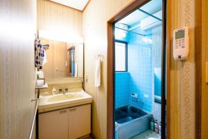 富士吉田的住宿－旭陽度假屋，一间带水槽和蓝色淋浴的浴室