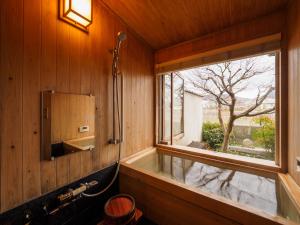 ein Bad mit einer Badewanne und einem Fenster in der Unterkunft 100 years old traditional Kyoto Machiya townhouse - K's Villa in Kyoto