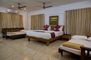 a hotel room with three beds and curtains at Shoolin Resorts in Manipal