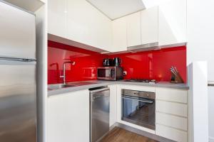a kitchen with red walls and white cabinets at Leichhardt Self-Contained Modern One-Bedroom Apartment (9NOR) in Sydney