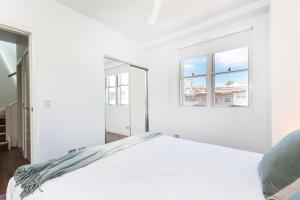 a white bedroom with a bed and two windows at Leichhardt Self-Contained Modern One-Bedroom Apartment (9NOR) in Sydney