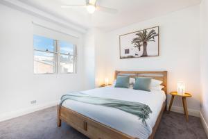 a white bedroom with a bed and a palm tree at Leichhardt Self-Contained Modern One-Bedroom Apartment (9NOR) in Sydney