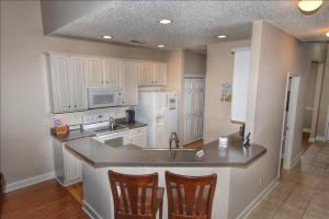 a kitchen with white cabinets and a counter with chairs at 2215 The Havens townhouse in Myrtle Beach