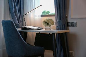 a desk with a chair and a lamp and a vase of flowers at Hanoi Fiesta Central Hotel and Spa in Hanoi