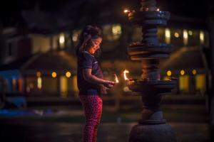 una mujer parada junto a una fuente con una vela en The World Backwaters, Alleppey, en Kumarakom