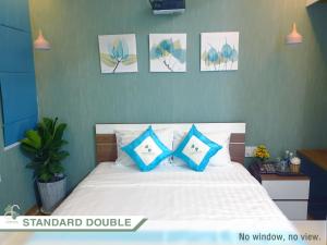 FLORA Hotel Phu Quoc في فو كووك: غرفة نوم مع سرير ووسائد زرقاء وبيضاء