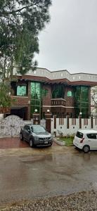 two cars parked in a parking lot in front of a building at Executive Galaxy Guest House in Islamabad