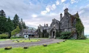 an old castle with a grassy yard in front of it at Ardanaiseig Hotel in Kilchrenan