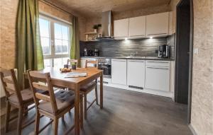 Nice Home In Olbernhau With Kitchen في Pfaffroda: مطبخ مع طاولة وكراسي ومطبخ مع دواليب بيضاء