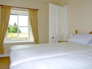 a bedroom with a white bed and a window at Roddy's Cottage in Glenelg
