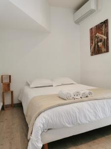 a white bedroom with a bed with towels on it at Le Saint Jean in Barbentane