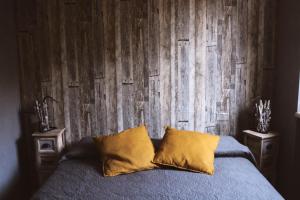 a bed with two pillows in front of a wooden wall at ApartHotel Le Sirene - CHALET in Tivoli