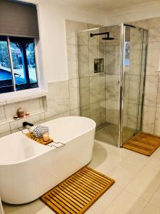 a white bath tub in a bathroom with a shower at Bellbird House in Cessnock