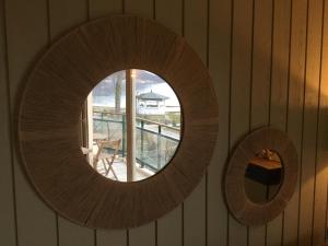 a round mirror on a wall with a window at Studio les pieds dans l'eau in Duingt