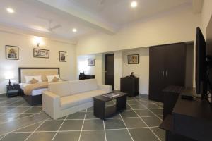 a living room with a white couch and a bed at Mimosa Udaipur in Udaipur