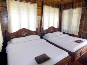 two twin beds in a room with windows at Khao Kho Lucky Hill Resort in Khao Kho