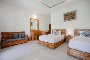 乌鲁瓦图WIRA Homestay & Spa的一间卧室配有两张床、一把椅子和镜子