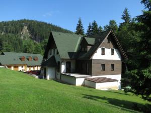 uma casa grande numa colina com um campo verde em Pension Skály em Teplice nad Metují