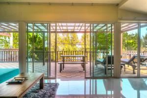ein Haus mit Glastüren und einer Veranda mit einer Bank in der Unterkunft Palm Beach Resort in Pran Buri