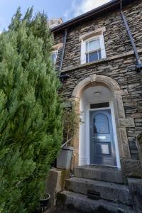 a stone house with a blue door and a tree at Ashleigh House - Room Only in Windermere