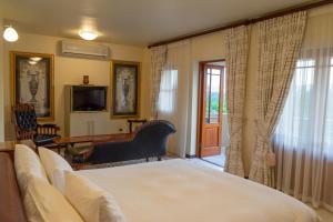 a bedroom with a bed and a desk and a television at Calitzdorp Country House in Calitzdorp