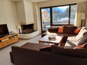 un soggiorno con divani, TV e camino di Apartment in Lenzerheide a Lenzerheide