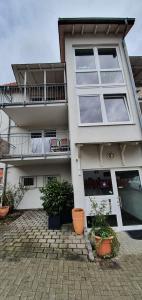 a white building with potted plants in front of it at Outletcity Ferienwohnung Wohnung 1 in Metzingen