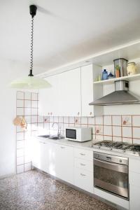 La cuisine est équipée de placards blancs et d'un four avec plaques de cuisson. dans l'établissement IseoLakeRental - Casa La Rondine, à Predore