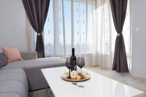 een woonkamer met een bank en een tafel met wijnglazen bij Niko's Sea View Apartments Deluxe in Nesebar