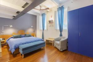 a bedroom with a blue bed and a chair at Malagigi Guest House in Ferrara