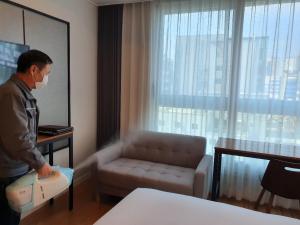 Um homem num quarto de hotel com uma mala. em The Mains Hotel em Cheonan