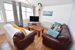 a living room with a leather couch and a table at Drift Away Apartment in Westward Ho