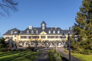 einen Blick nach außen auf ein großes gelbes Gebäude mit Bäumen in der Unterkunft Jagdschloss Hotel Niederwald in Rüdesheim am Rhein