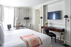 um quarto de hotel com uma cama, uma secretária e um computador em J.K. Place Paris em Paris