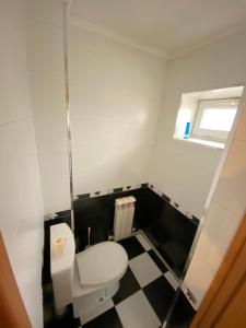 a bathroom with a white toilet and a checkered floor at Apartment na Kirova 37 in Pyatigorsk