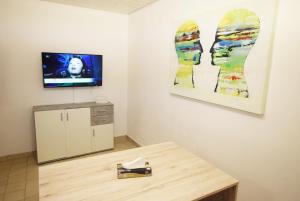 a room with a table and a tv on a wall at Apartment Möhringen in Stuttgart