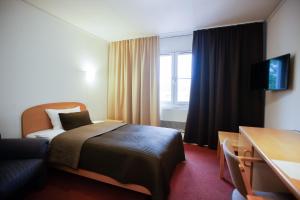 une chambre d'hôtel avec un lit et une chaise dans l'établissement Swedish Village Hotel, à Timachiovsk