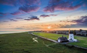 a building in a field with the sunset in the background at Clifton Arms Hotel in Lytham St Annes