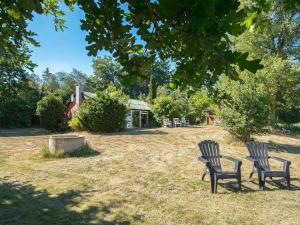 deux chaises assises dans l'herbe sous un arbre dans l'établissement 6 person holiday home in Br dstrup, à Hårup