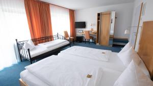 a hotel room with two beds and a desk at Hotel Elite in Karlsruhe