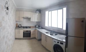 a small kitchen with a refrigerator and a sink at Apartment Anis Nador Al Jadid in Nador