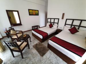 a hotel room with two beds and a chair at Tranquil Villa in Nuwara Eliya