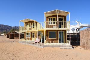 a yellow house on the beach with a boat at Sina Star Camp in Nuweiba