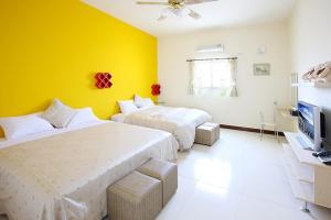 um quarto com duas camas e uma televisão em Penghu Jack Family B & B em Magong